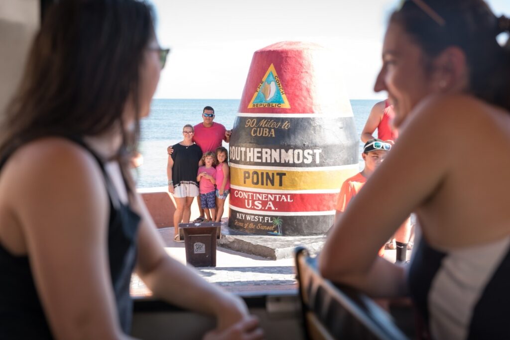 People taking a photo from the Southernmost Point in Key West, Florida