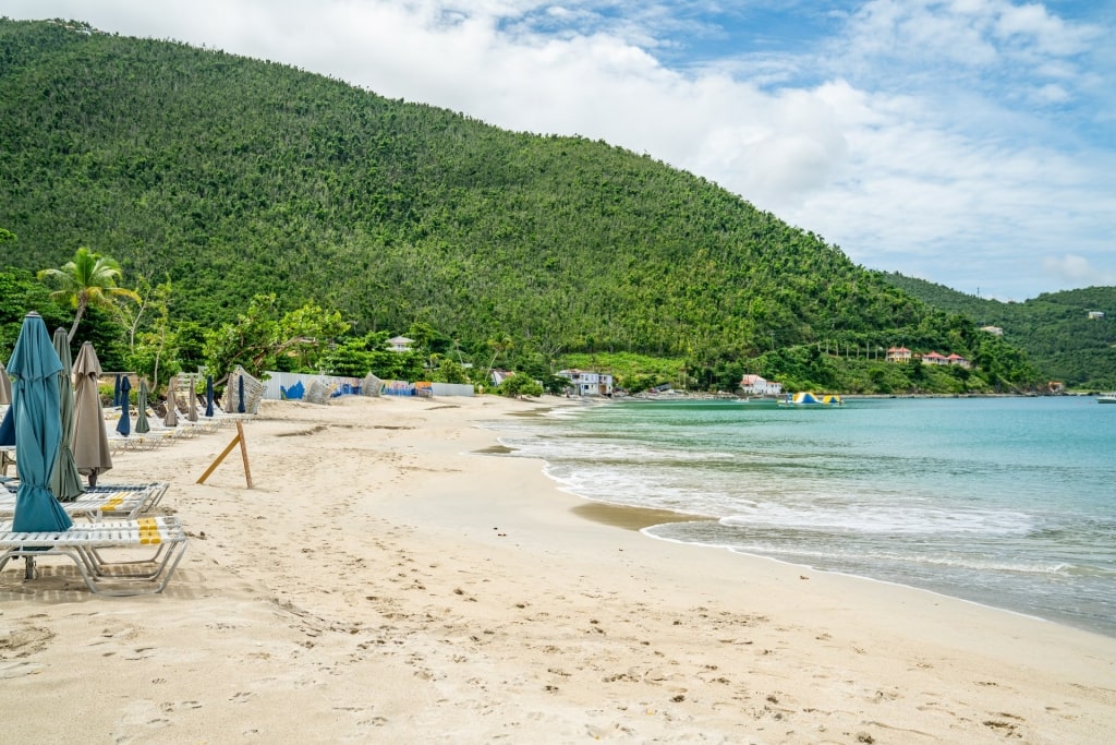 Stretch of white sand in Cane Garden Bay Beach with mountain