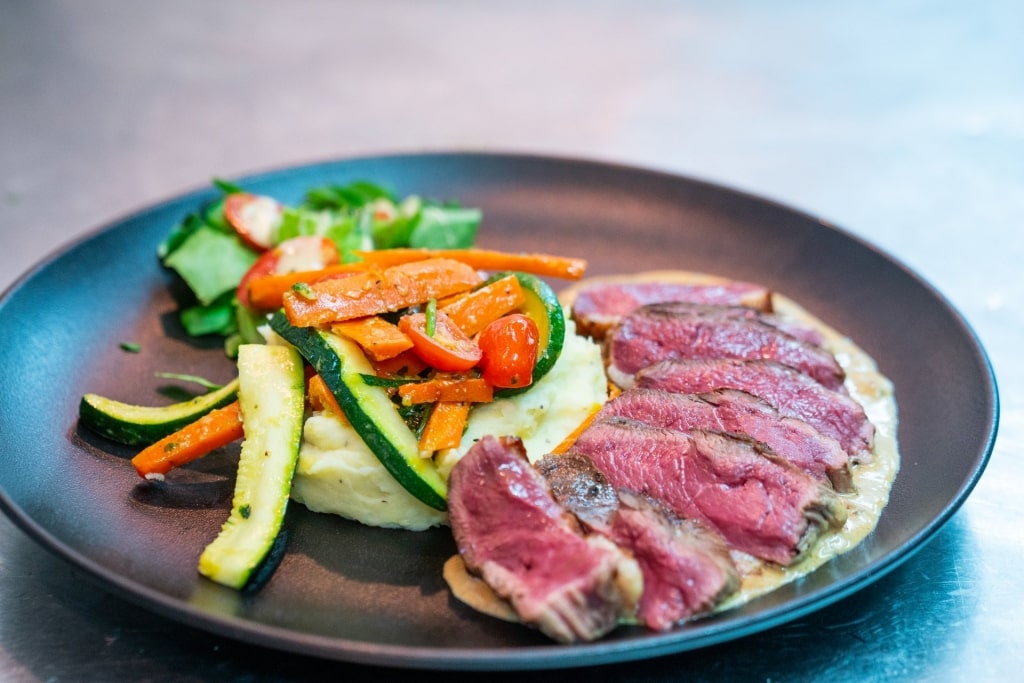 Plate of steak with mashed potato and veggies on the side