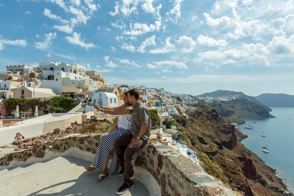 Couple taking a photo near the cliff in Oia, Santorini, one of the best European honeymoon destinations