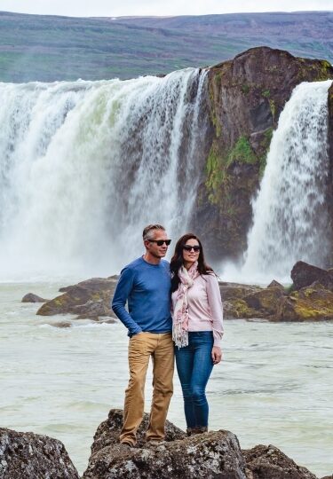 Couple standing on rock in Godafoss waterfall, Iceland