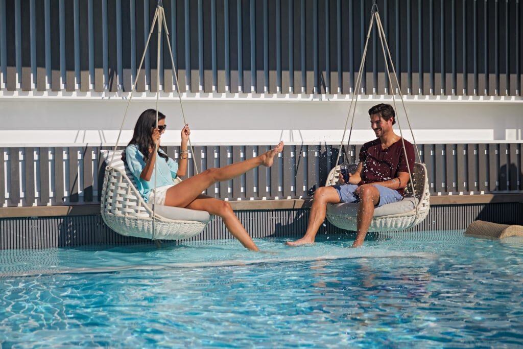 Couple sitting on a swing by the pool