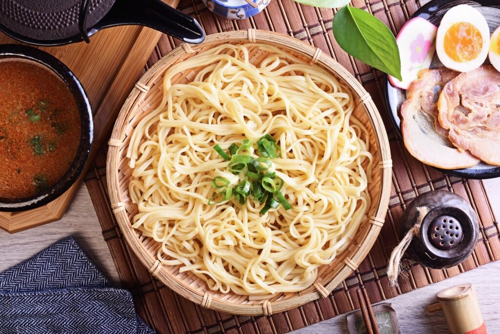 Separate bowls of noodles and broth on a table