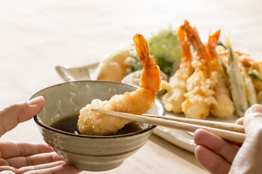 Tempura being dipped into the sauce