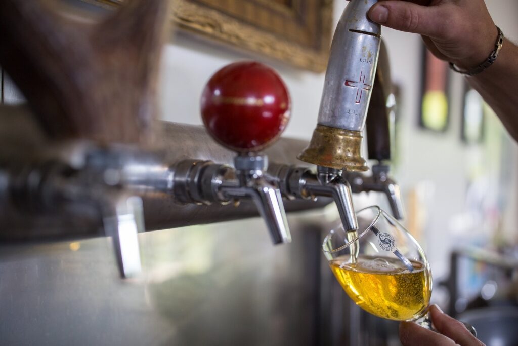 Man refilling glass with beer on tap