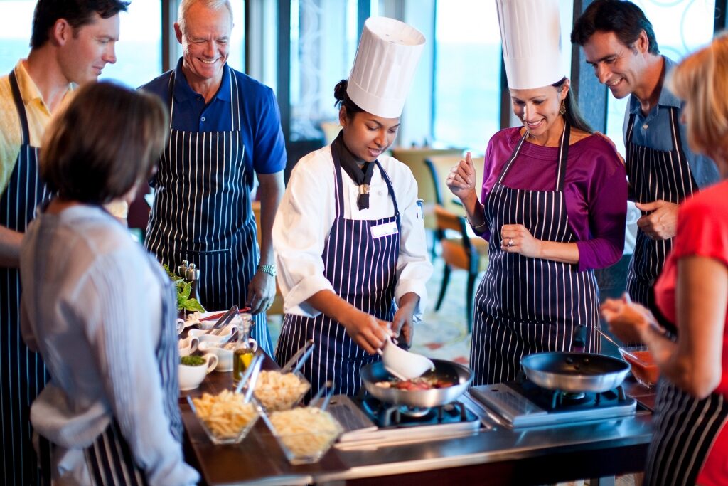 Guests taking cooking class with chef on a cruise