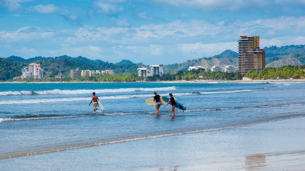 People carrying surfboards at Playa Jaco beach
