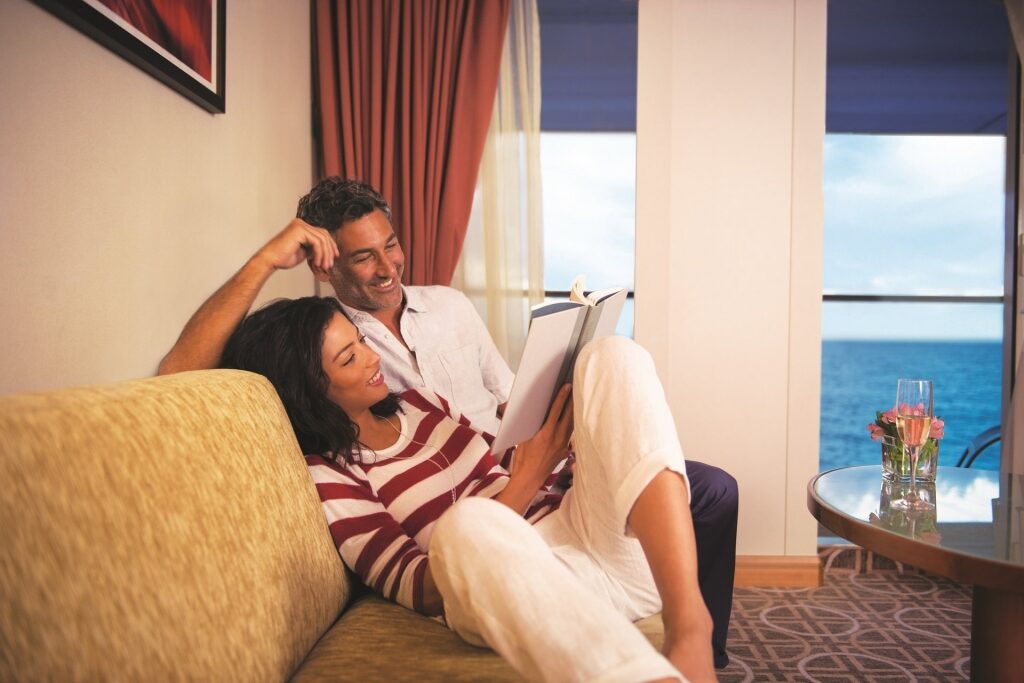 Couple reading inside a stateroom on a cruise