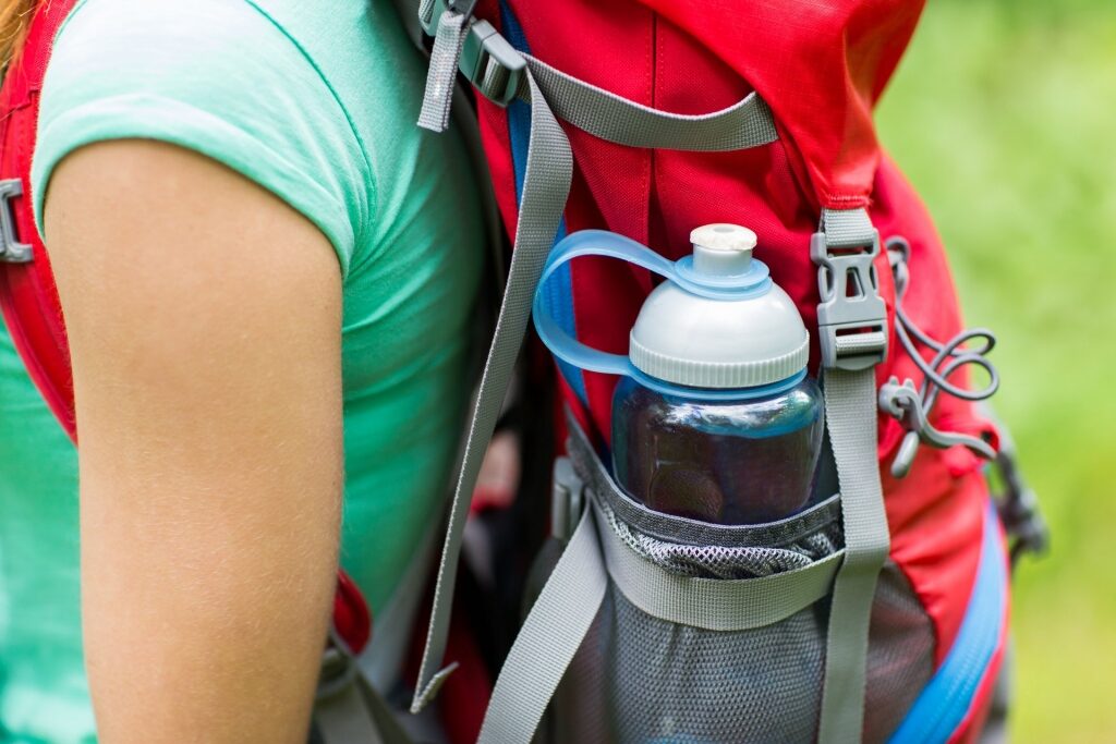 Woman carrying red backpack with water bottle 