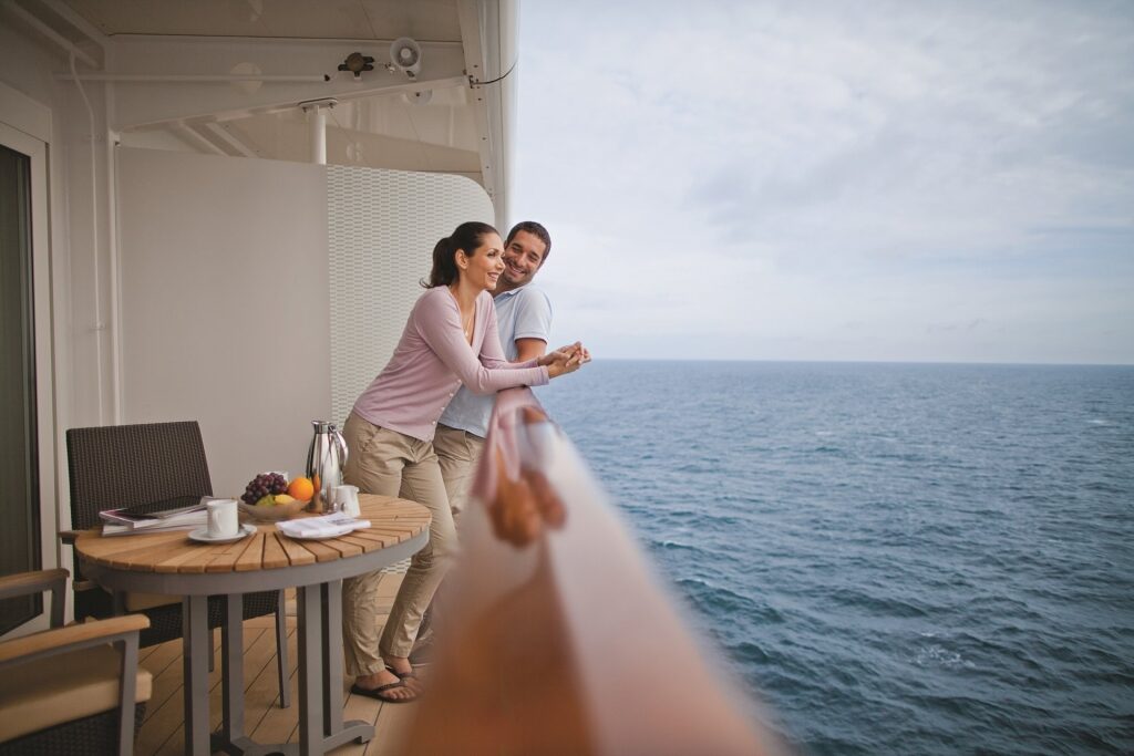 Couple on a cruise standing on Celebrity Stateroom balcony
