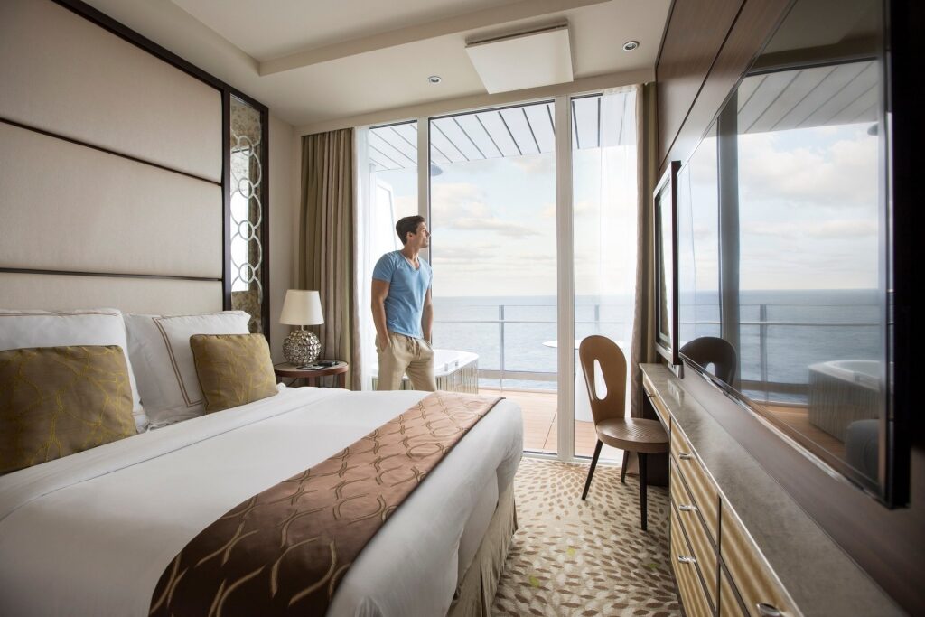 Man looking out Celebrity Stateroom glass door while seasick on cruise