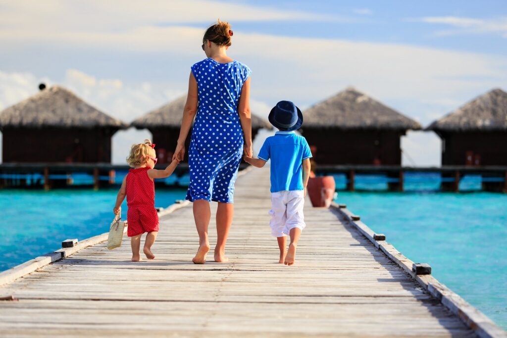 Woman and two toddlers walking on boardwalk at the beach