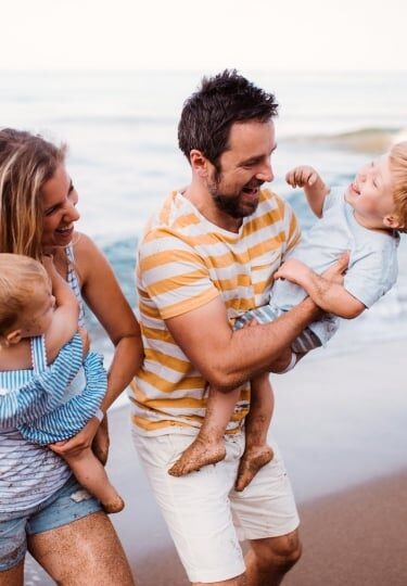 Couple playing with their toddlers on the beach