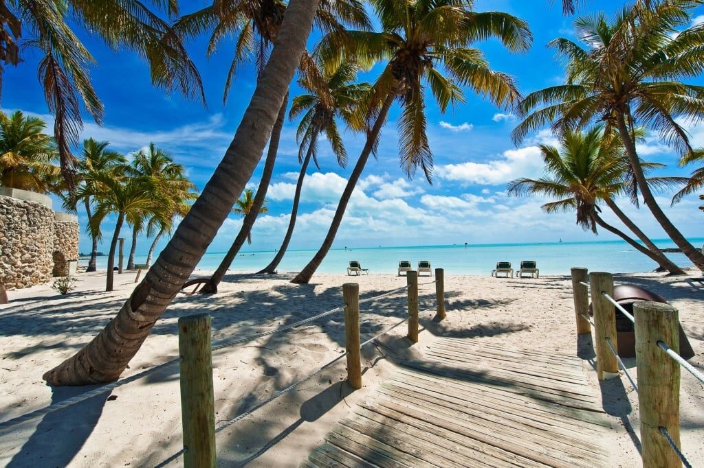 Boardwalk leading to palm trees and white sand beach in Key West, Florida 