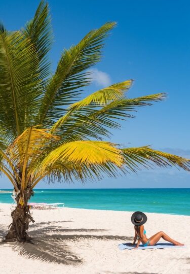 Woman on a white sand beach lined with palm trees