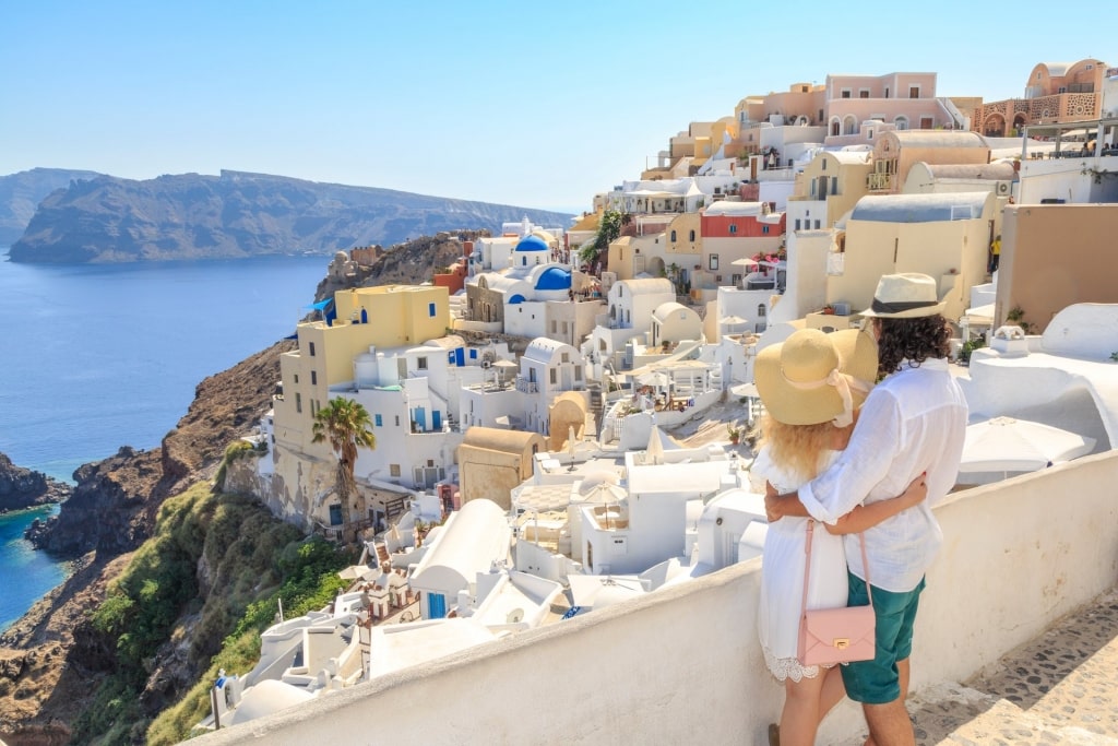 cuplu poartă pălării în timp ce se uită la Santorini Grecia peisaj