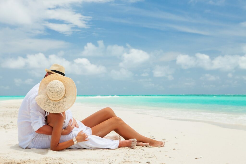 Couple sitting on white sand beach