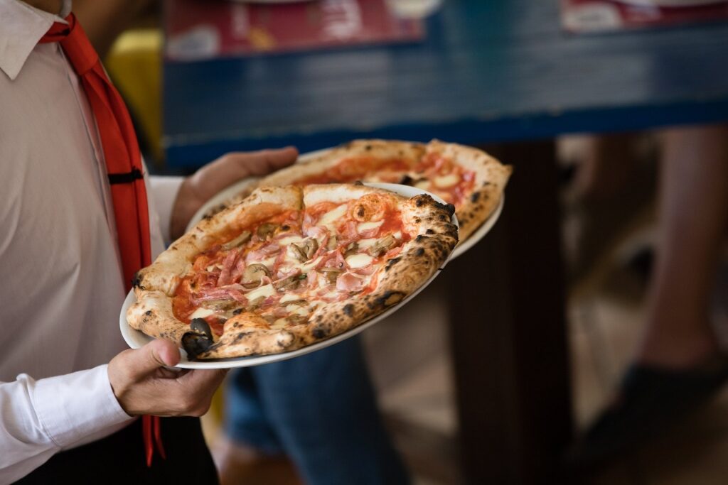 Staff holding Italian pizza