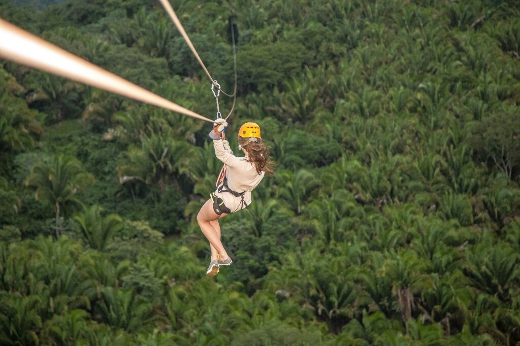 Woman riding a zipline with lush trees