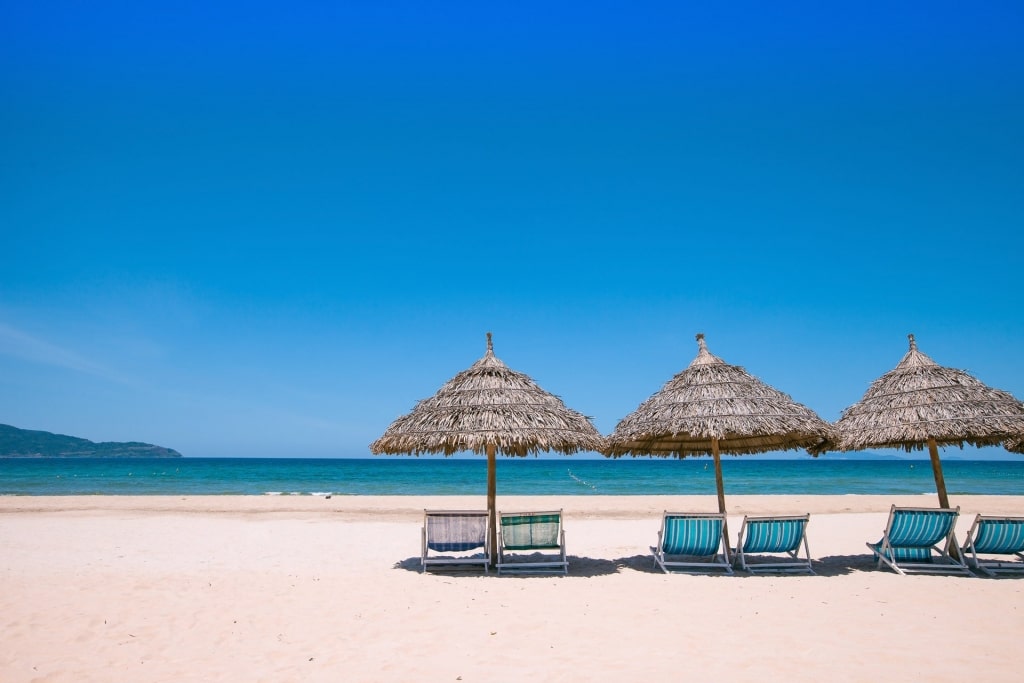 Blue waters of My Khe Beach with beach chairs