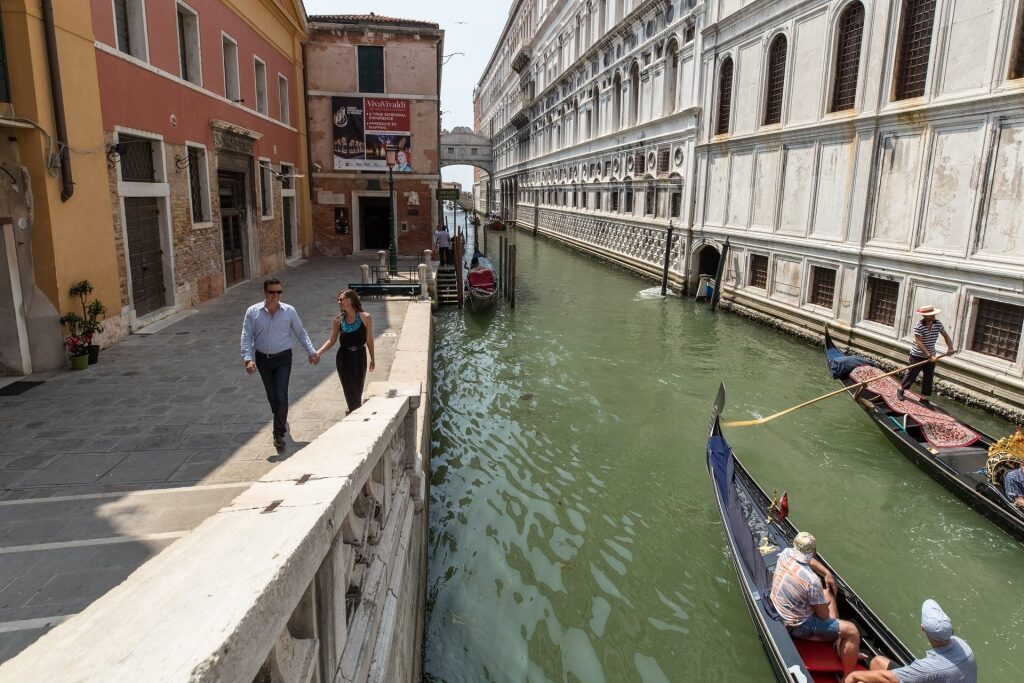 Couple walking in Venice with view of canal and gondola ride