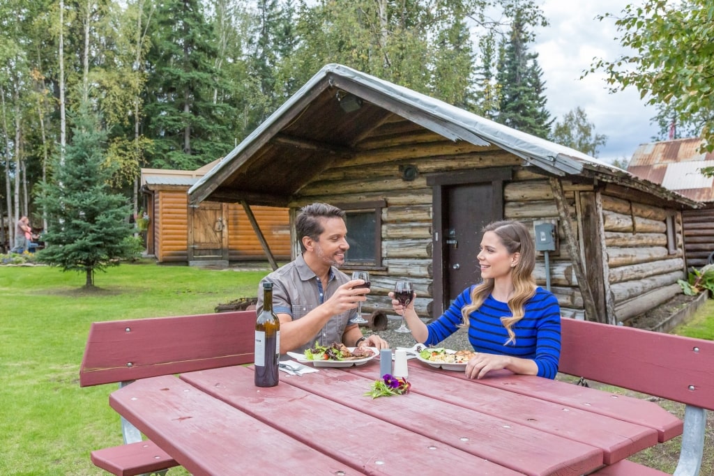 Couple eating al fresco amidst Alaska cabins