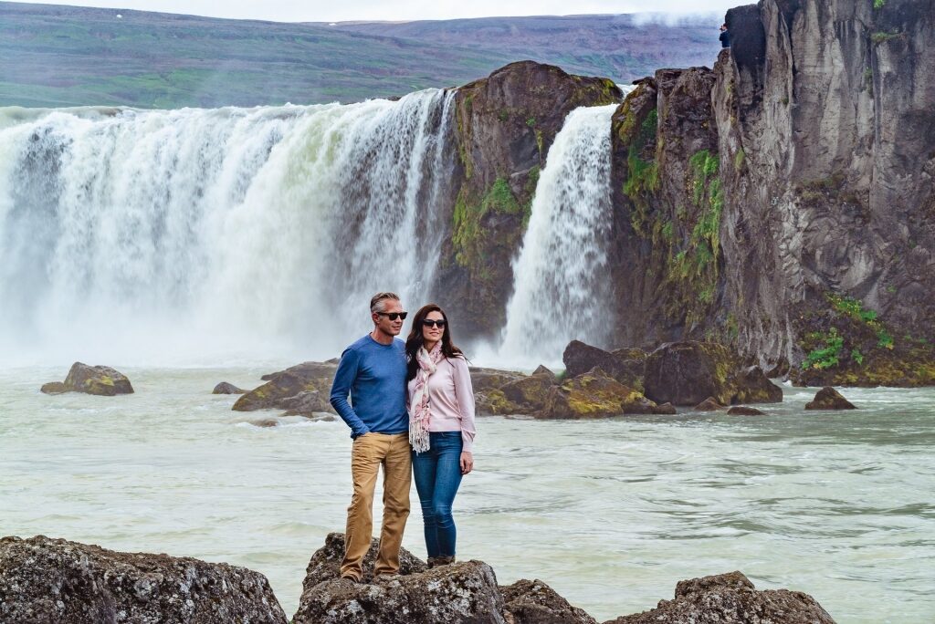 Couple sightseeing in Godafoss waterfall