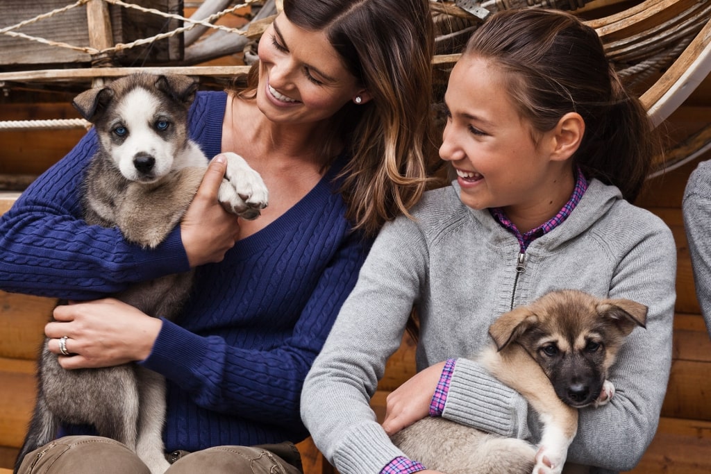 Family petting Alaskan puppies