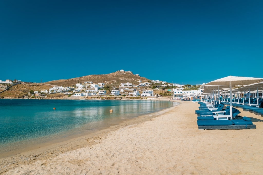 Golden sands of Ornos Beach with blue beach chairs