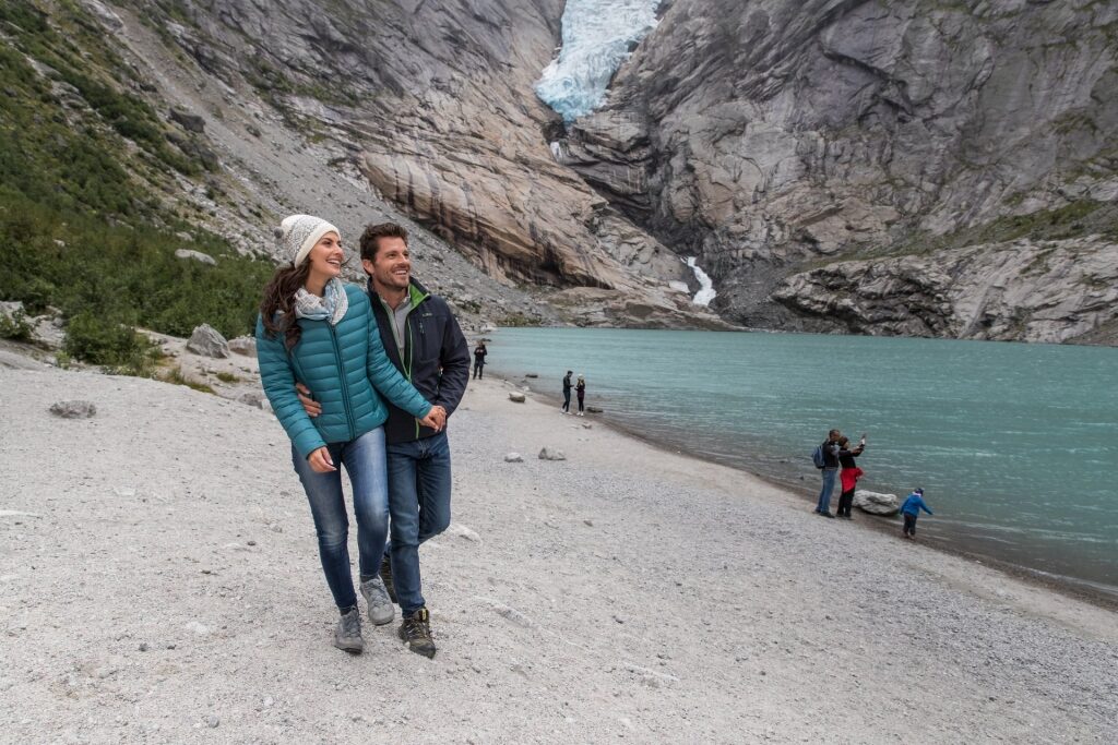 Couple walking along Briksdal Glacier