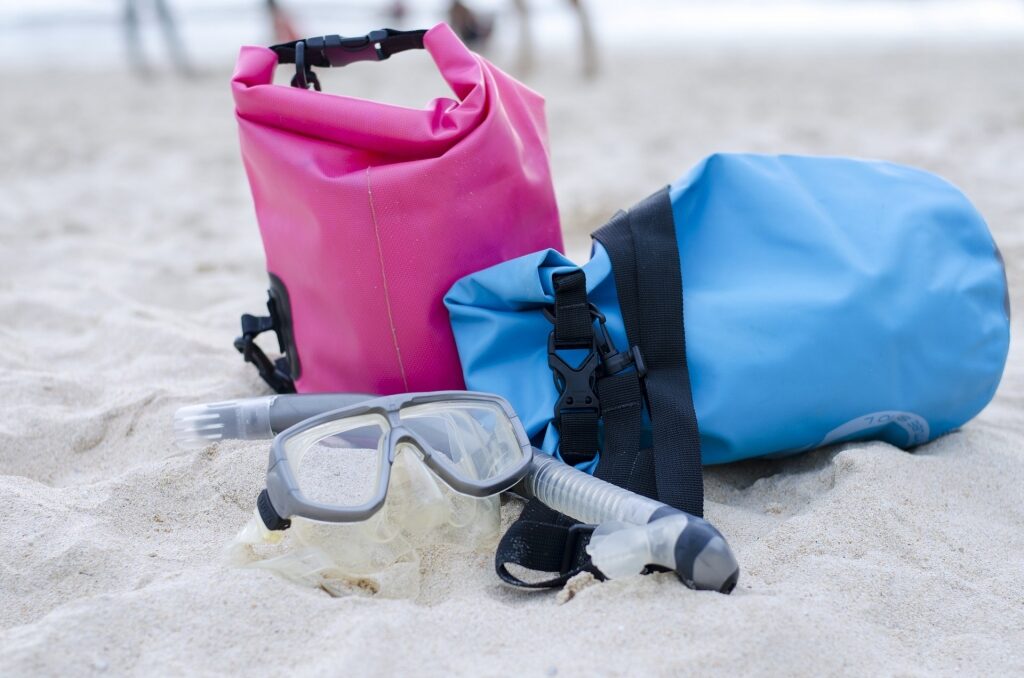 Blue and pink waterproof bags on a sandy beach