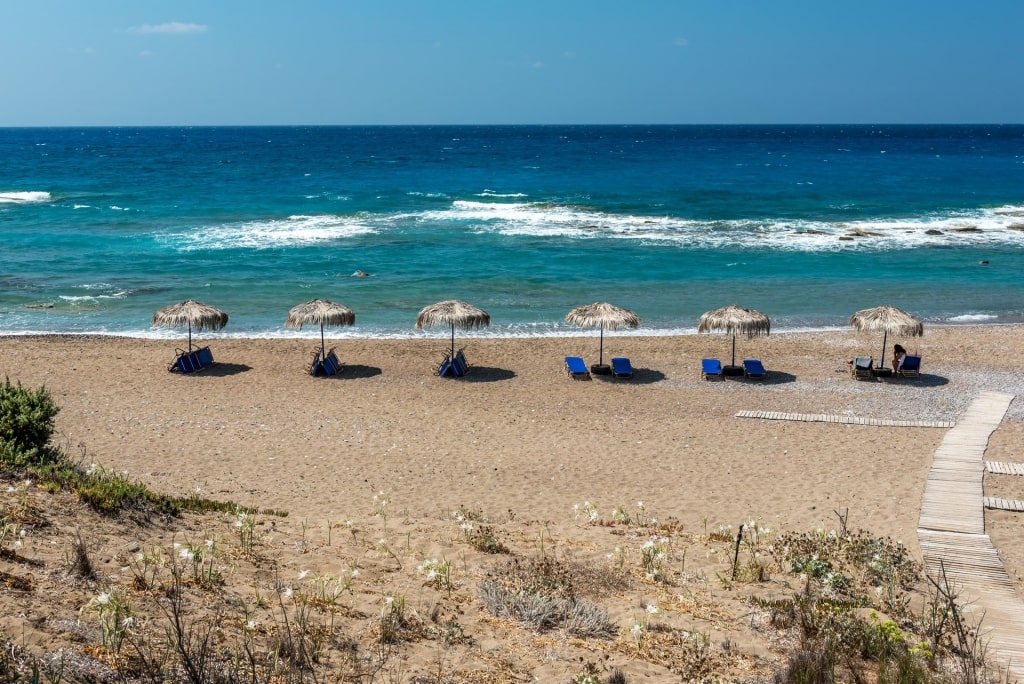 Beach umbrellas lined up on the golden sands of Limni Beach