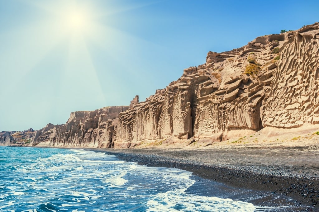 Black sands of Vlychada Beach with cliffs