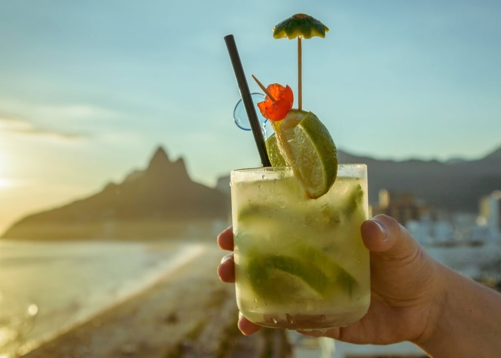 Man enjoying a glass of caipirinha from the beach