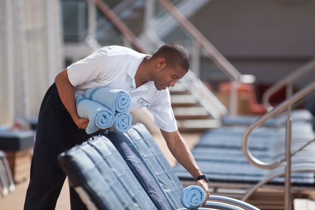 Cruise staff putting fresh towels on the pool chairs