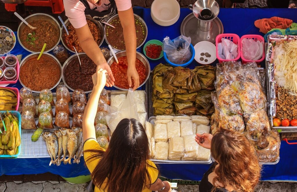 People buying snacks from a stall in Bangkok