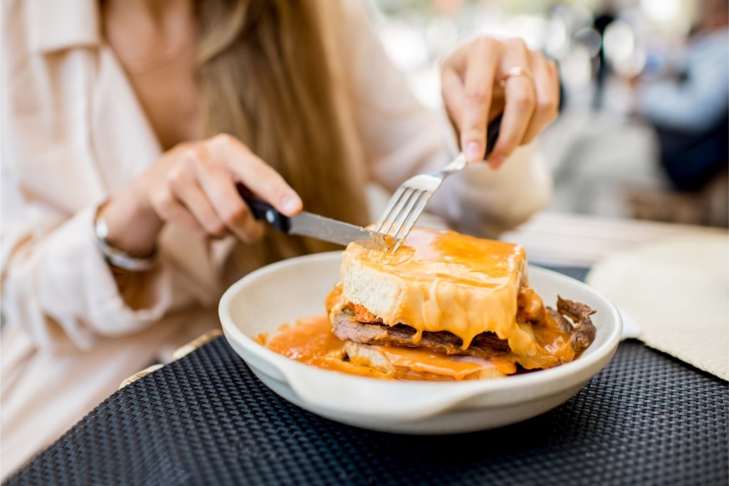 Person eating tasty francesinha