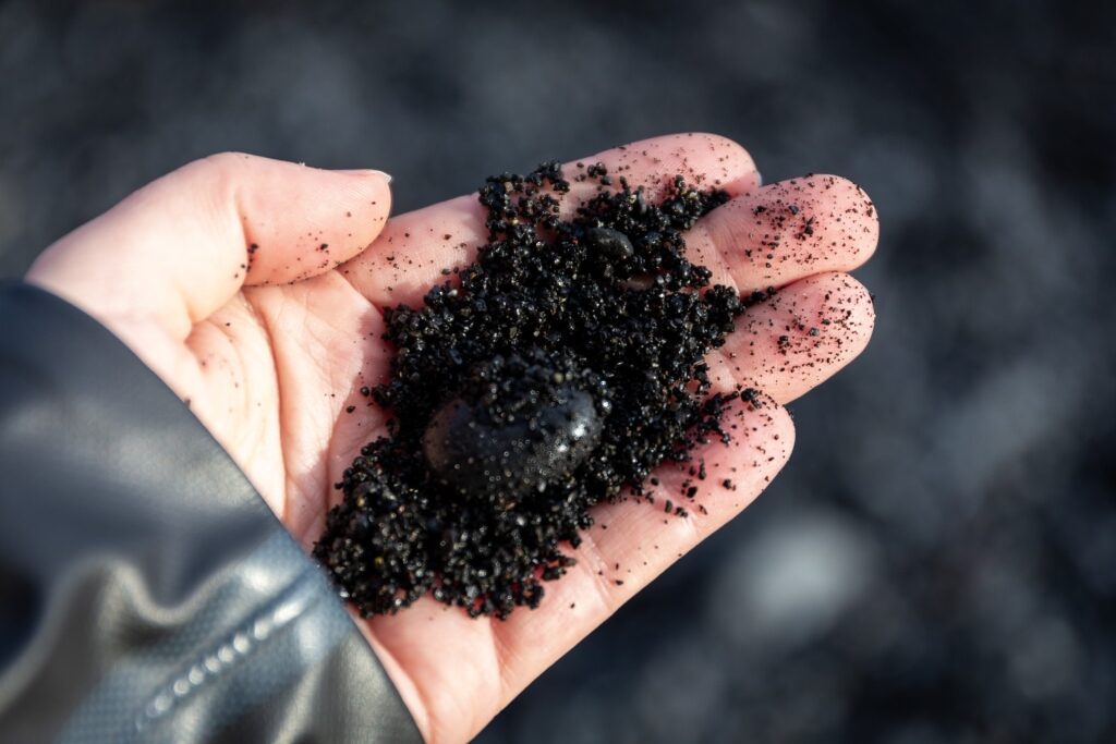 Person inspecting black sands