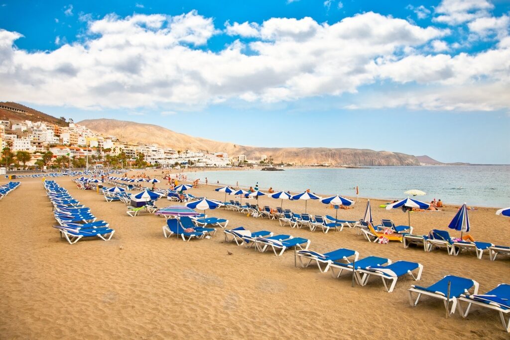 Golden sands of Playa de Los Cristianos with beach chairs
