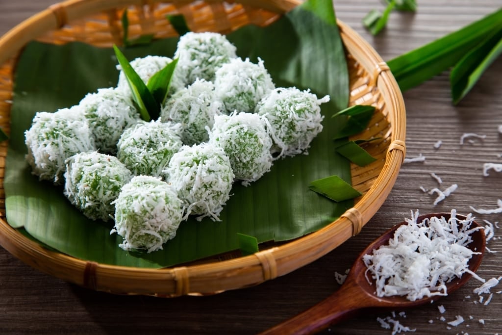 Plate of Balinese dessert klepon coated with grated coconut, served on banana leaves