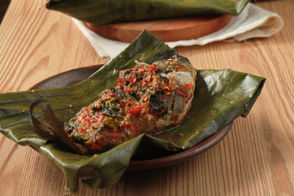 Plate of pepes ikan wrapped in leaves