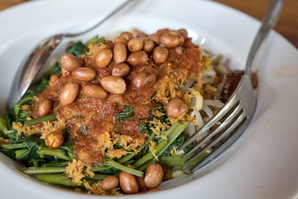 Plecing kangkung spinach salad served on a white plate