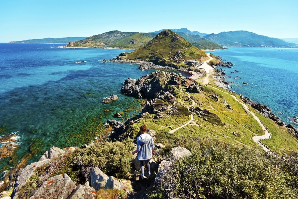 Woman walking down Parata Point in Corsica, France