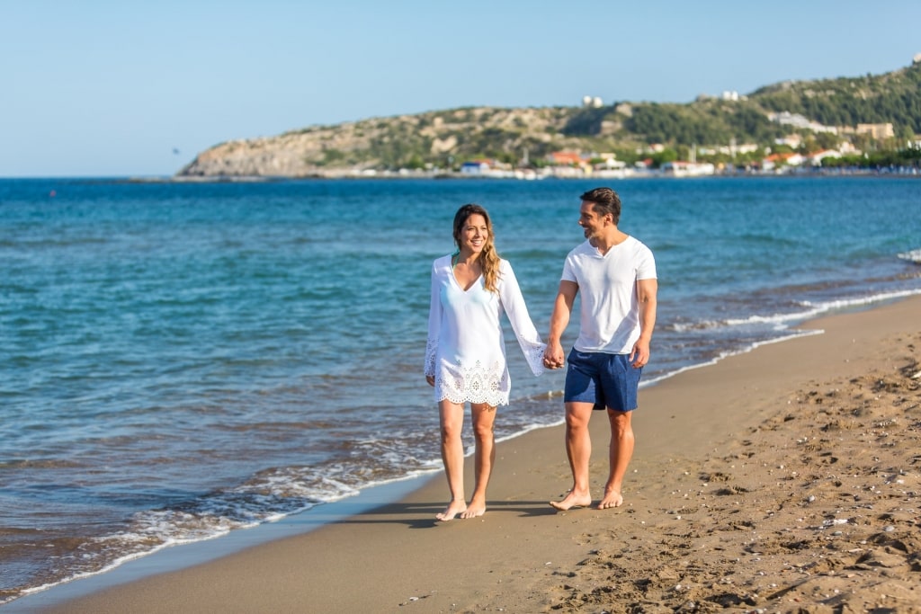 Couple walking the fine sands of Faliraki Beach in Rhodes, Greece