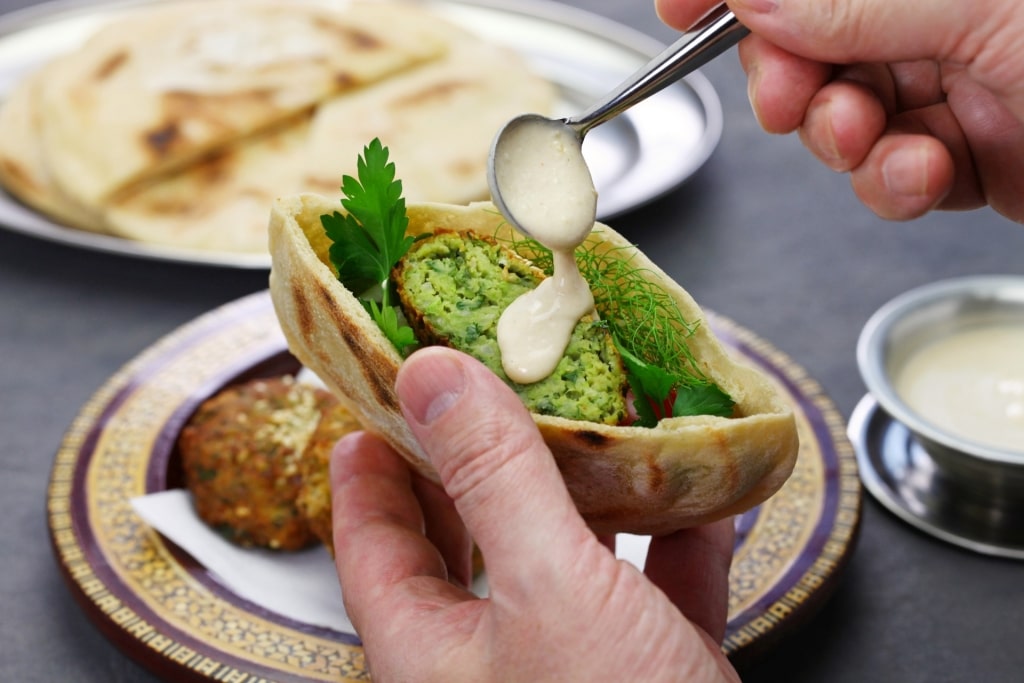 Man pouring tahini dip 