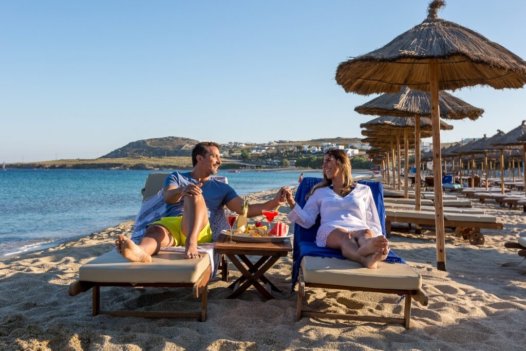 Couple relaxing on Kalafatis Beach in Mykonos, Greece