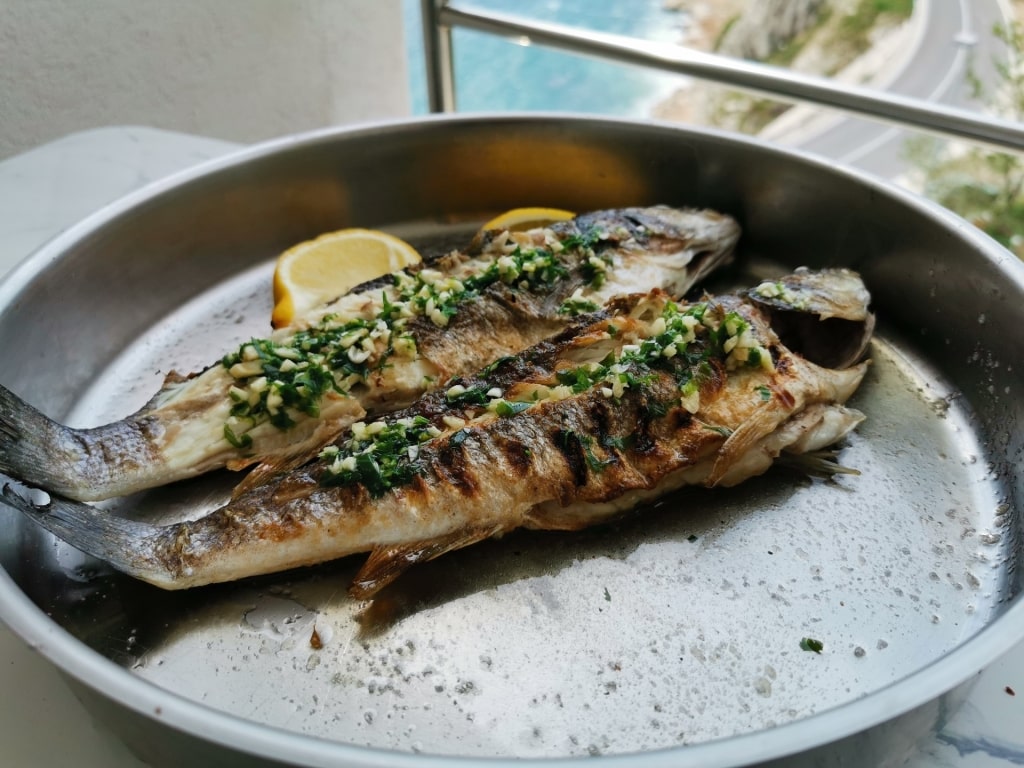 Grilled Adriatic fish on a plate with lemon on the side