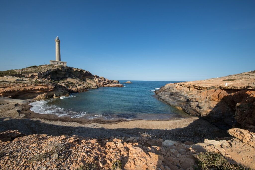 View of the beach with Faro Cabo de Palos in Cartagena, Spain