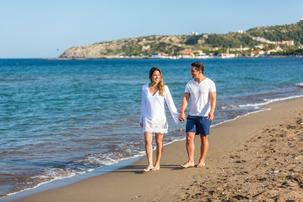 Couple walking along Faliraki Beach, Rhodes