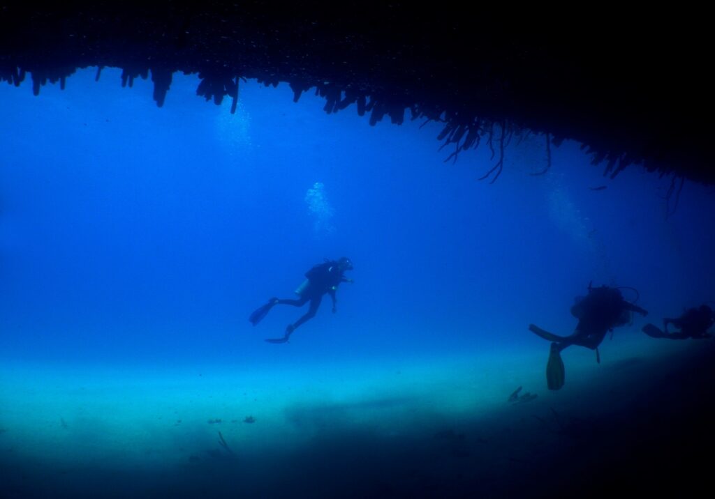 People scuba diving in SS Antilla Shipwreck